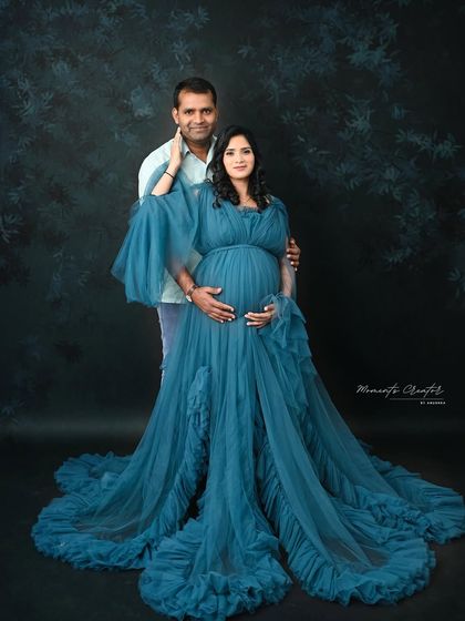 A classic couple's portrait in a stunning blue gown. The partner's supportive embrace around the baby bump is a central theme in my couple's maternity photography.
