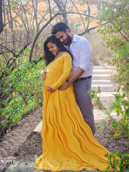 A tender embrace between the expecting couple, tucked away in a quiet, leafy nook. The natural setting makes this romantic maternity photo feel so intimate and special.