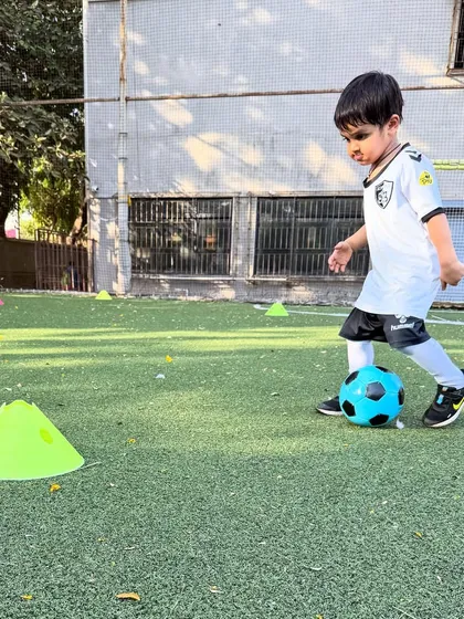 One of our youngest players from the U4 group carefully dribbles around a cone, taking his first steps in our fun and encouraging learning environment.