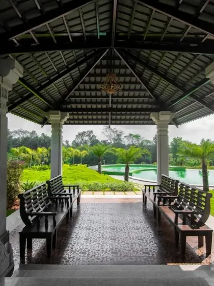 A covered gazebo with stone pillars offers a shaded spot to rest and enjoy views of the pool and surrounding gardens.