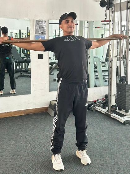 Holding a shoulder stretch with a stick. This is great for posture and relieving tension.