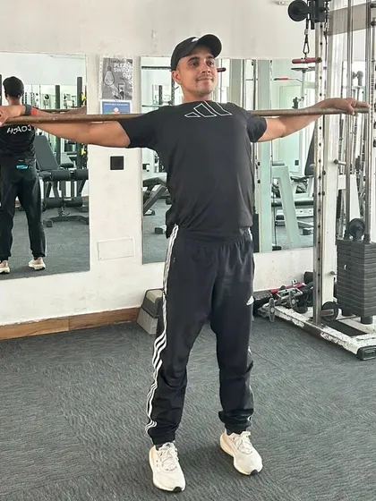 Holding a shoulder stretch with a stick. This is great for posture and relieving tension.