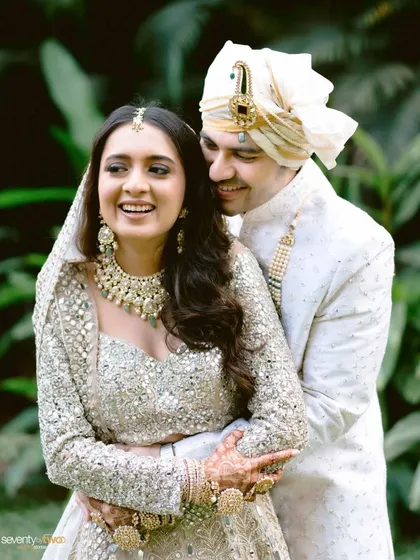 A joyful, candid portrait of the couple, their smiles infectious, captured in a lush green setting at their Alibaug wedding.