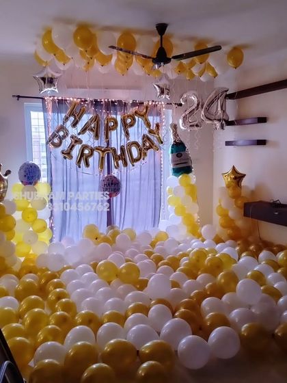 A room filled with 600 yellow and white balloons for a grand birthday surprise.