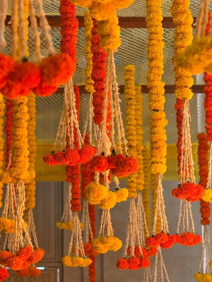 A ceiling view of our Haldi decor, featuring dense hangings of orange and yellow marigold garlands. This traditional floral canopy created a vibrant and auspicious atmosphere for the ceremony.