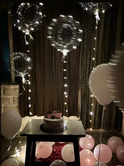 A closer look at the intimate birthday setup. The bobo balloons with fairy lights inside create a magical, twinkling effect in the dimly lit room.