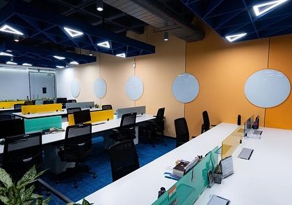 An open workspace at Tata Consumer Products, where the long lines of desks are softened by the presence of plants. This design promotes a sense of openness while still providing visual comfort.