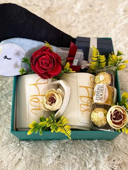 A perfect gift to celebrate a new chapter. This engagement hamper for a couple includes a matching set of "His" and "Hers" mugs, delicious Ferrero Rocher chocolates, and a cute penguin eye mask, all elegantly arranged to congratulate the happy pair.