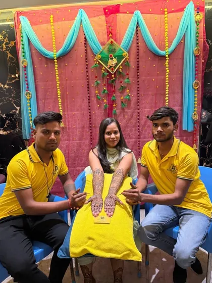 My artists with a client at her mehndi function. You can see the beautiful, intricate design covering her hands and arms, ready for her big day.