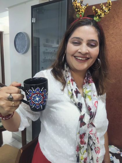 A smiling participant shows off her completed dot mandala mug at the Christmas-themed art get-together.