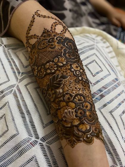 A clear shot of the intricate patterns on the forearm. This design features a mix of leaves, flowers, and traditional Indian motifs.