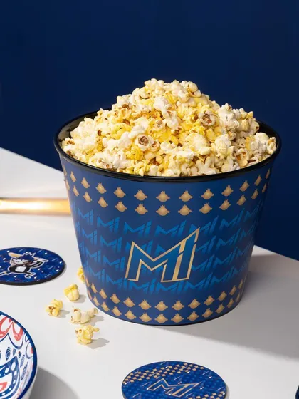 Adding popcorn to the Mumbai Indians merchandise shot creates a "game day" atmosphere. This small styling addition tells a story and makes the scene more relatable and fun.
