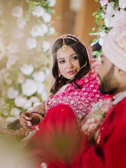 A quiet, candid moment between the bride and groom during their wedding ceremony. The bride's loving gaze towards her partner is framed beautifully by the floral decor.