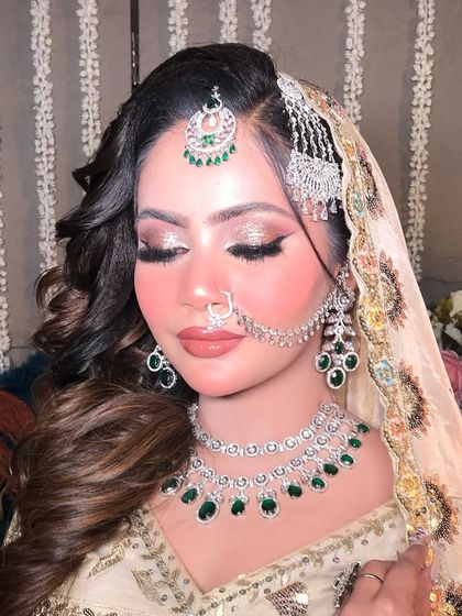 A close-up of my Pakistani bridal glam. The look features soft, wavy hair, a diamond and emerald jewelry set, and a flawless makeup base with defined, winged eyeliner.