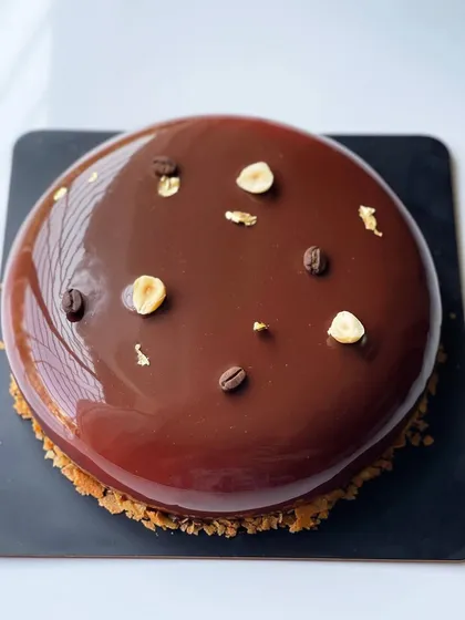 Another angle of the glossy, perfect glaze on the Coffee Hazelnut entremet, garnished simply with toasted hazelnuts and coffee beans.