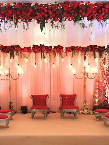 A grand and royal Vidhi Mandap setup, featuring rich red florals, traditional candelabras, and ornate silver and red seating for the bride and groom.