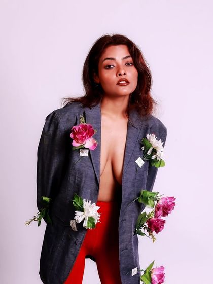 A confident and artistic pose. The contrast between the structured blazer and the soft, organic flowers is visually compelling.