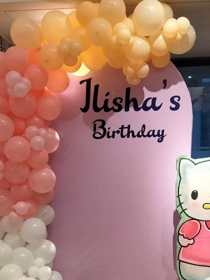 A simple and cute photo booth area for the Hello Kitty party, with a balloon garland and character cutout.