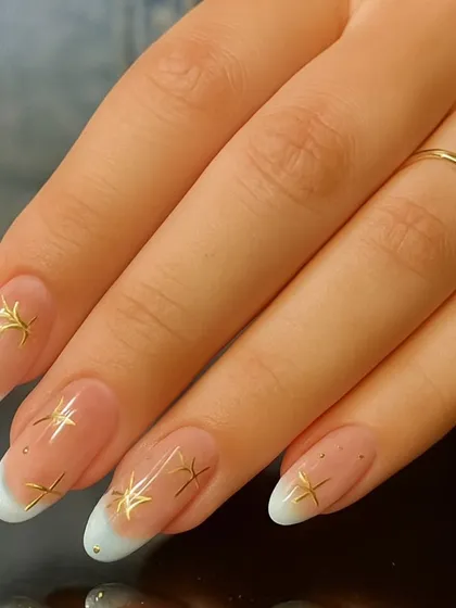 A modern twist on a classic. This clean French manicure is elevated with delicate gold star embellishments and tiny rhinestones, adding a touch of celestial charm.