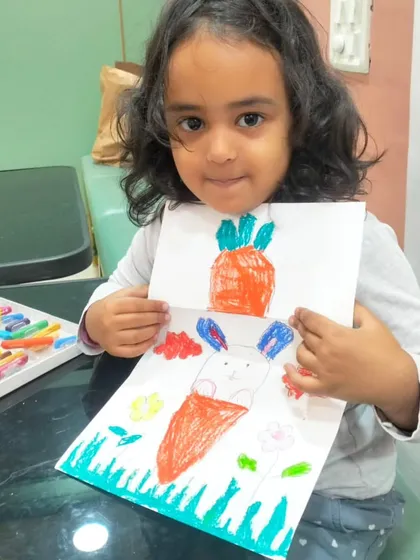 This young artist proudly displays her clever carrot and bunny drawing. It's a simple paper craft that combines drawing, coloring, and a fun surprise element.