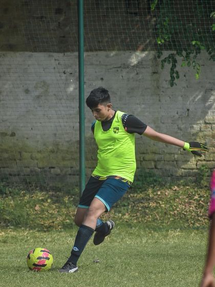 A player in a practice bib kicks the ball, likely during a pre-game warm-up or training drill.