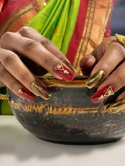We crafted these stunning nails for a traditional Maharashtrian look, blending rich red with metallic gold chrome. The design incorporates geometric accents and is perfectly complemented by the bride's green bangles, showcasing our skill in creating cohesive, festive nail art.
