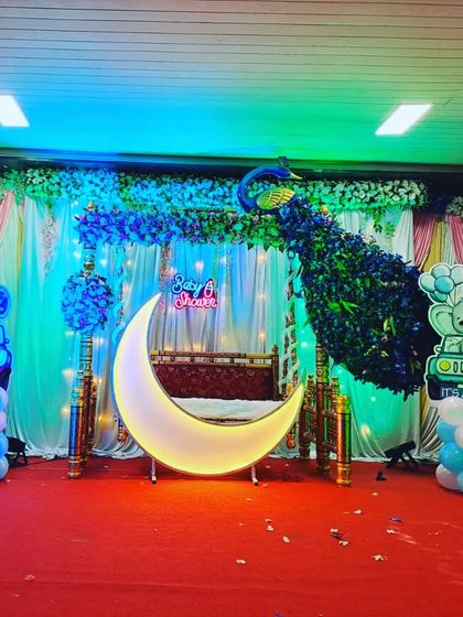 The peacock-themed baby shower setup with blue lighting, creating a serene and magical ambiance for the 'dohale jevan' ceremony.