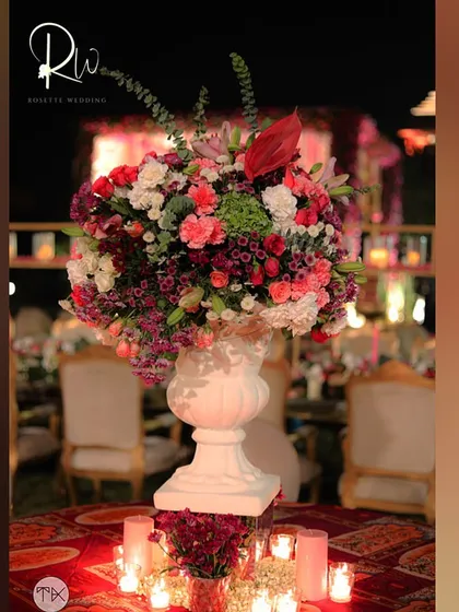 A large, classic urn filled with a colorful bouquet of flowers, used as a statement piece at a traditional wedding.