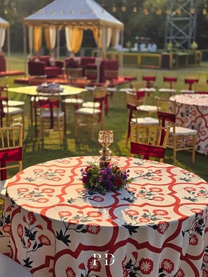 Custom-designed table linens with red and white floral patterns for a Sufi-themed Sangeet. This detail ties the entire decor together, from the large tents to the individual place settings.