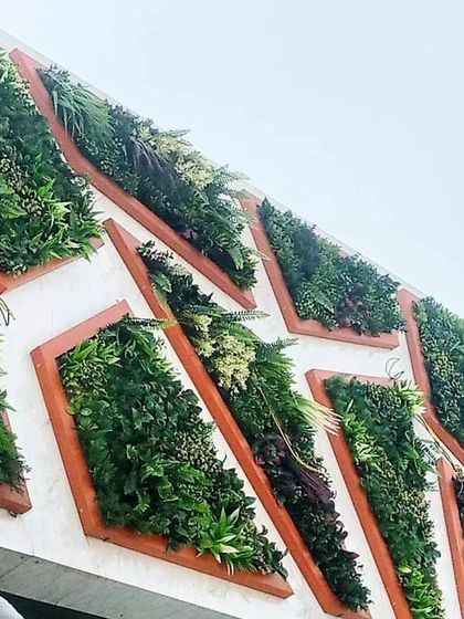This exterior wall features a unique geometric design. I used wood-framed, diamond-shaped planters filled with various artificial plants to create a modular, 3D art piece.
