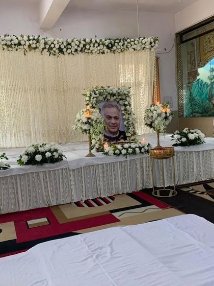 A serene and respectful stage decoration for a prayer meeting. I used all-white flowers and drapes to create a peaceful and dignified atmosphere.