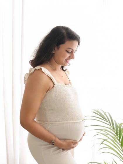 A sweet and simple portrait of a mom-to-be by the window. The soft, natural light gives her a beautiful glow as she looks down at her bump.