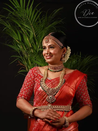This professionally captured photo showcases a complete South Indian bridal look. The makeup is designed to be bold yet elegant, with defined eyes and a warm lip colour that enhances the bride's features. Paired with an elaborate hairstyle and antique jewellery, this is a classic look for any traditional wedding ceremony.