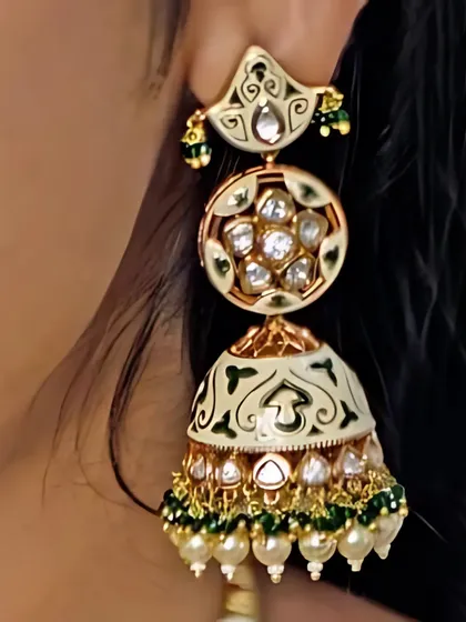 A close-up of a beautiful jhumka earring with intricate meenakari (enamel) work and kundan stones. These earrings are a work of art, perfect for adding a traditional touch to any outfit.