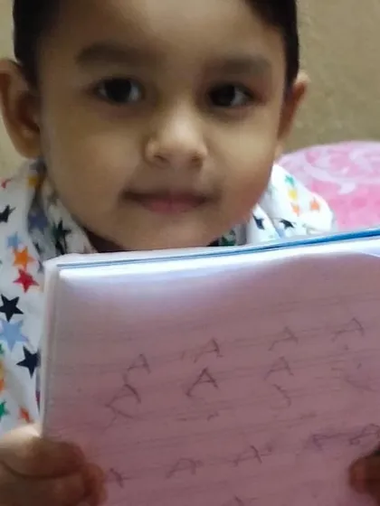 Here is a young student proudly showing his notebook filled with practice for writing the letter 'A'. Consistent, gentle practice is key to developing fine motor skills and confidence in handwriting.