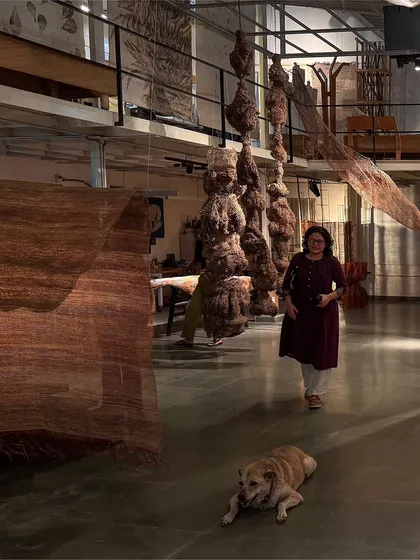 A moment in our studio during the 'Cu+Fibers' show. A visitor walks through the space, surrounded by hanging sculptures made of hemp, jute, and copper, with our studio dog resting nearby.