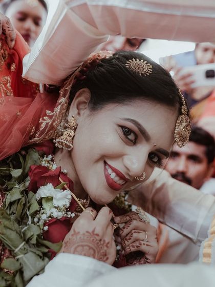 A close up shot of the bride's joyful expression as she is blessed during the ceremony. This image focuses on her happiness and the traditions of an Indian wedding.
