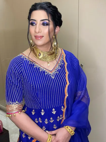The blue smokey eye adds a beautiful touch of drama, perfectly complementing her gold jewelry.