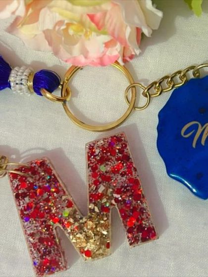 You can mix and match styles for a truly custom keychain. This set features a glittery initial 'M' paired with a solid blue charm personalized with the name 'Mittu'.