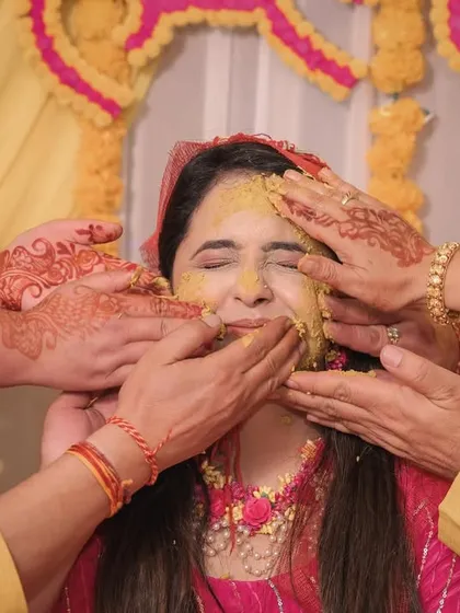 A close-up of the Haldi application, capturing the bride's expression of pure joy and the hands of her loved ones.