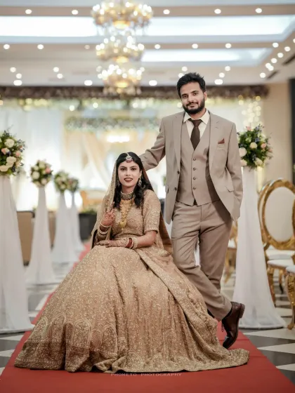 A grand portrait of the couple at their Walima reception, showcasing the bride's stunning gown and the elegant decor.
