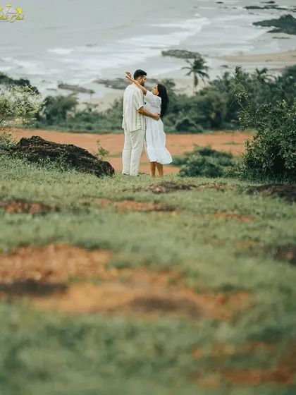 A wide shot capturing the couple amidst the green landscape of Goa, with the ocean in the background.