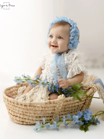 A profile shot of this lovely baby girl, capturing her happy smile and the delicate details of her lace bonnet.