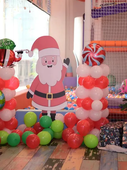 Our festive Christmas setup, with a tree, Santa cutout, and red and green balloon decorations.