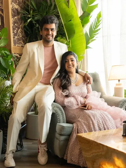 A relaxed portrait of the couple seated in a chic, plant-filled setting during their engagement party.