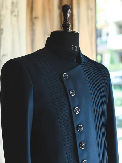This navy blue Indo-Western jacket showcases my love for texture and structure. The design features an asymmetrical closure with sections of precise pintucking and pleating, creating a modern, architectural look.