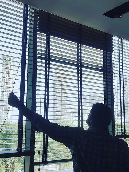Here I am adjusting a newly installed set of wooden blinds. I handle the complete installation to ensure they fit perfectly and operate smoothly for light control and privacy.
