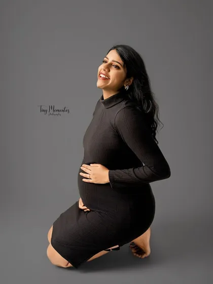 A joyful kneeling pose that feels both candid and beautifully composed. The simple black dress keeps the portrait modern and focused.