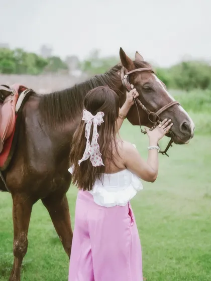 A view from behind shows a rider carefully tending to her horse, a quiet moment that speaks volumes about the connection.