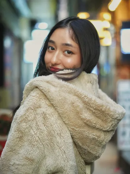 A playful over the shoulder look. The blurred lights of the market street create a beautiful bokeh that makes this night portrait feel magical and alive.